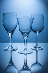 three crystal glasses on blue illuminated transparent background