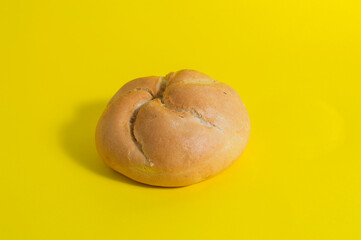 salty rustic Spanish bread roll isolated on yellow background