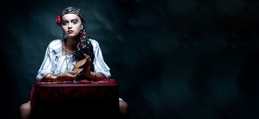 a portrait of a gypsy fortune teller mixing the tarot cards. - 423800914