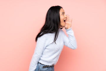 Teenager Chinese woman isolated on pink background shouting with mouth wide open to the side