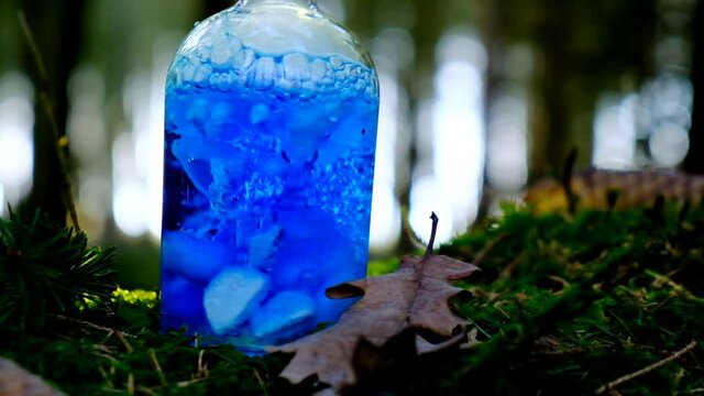 Magical blue smoking potion. herbal potion. Herbal elixir on a mossy stump on a blurred forest background.Magic Potion. Homeopathic medicine. Organic Cosmetics Concept