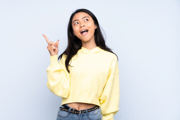 Teenager Chinese woman isolated on blue background intending to realizes the solution while lifting a finger up