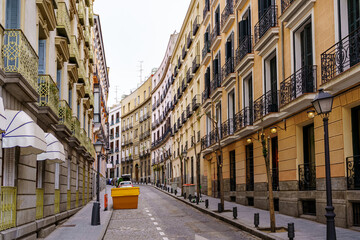 Narrow street in Madrid with typical balconies of the city and colored buildings.