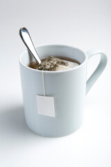 Cup of tea with tea bag and blank label on white background