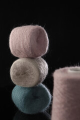 Small balls of yarn for hand knitting. Multi-colored soft fluffy wool. Natural mohair. Hobby and manual labor. Vertical photo on black background. Out of focus.