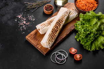 Delicious fresh shawarma with meat and vegetables on a dark concrete table
