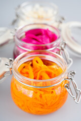 Homemade village fermented sauerkrauts, red cabbage and korean carrot in glass jars, gray background. Concept probiotics food, Supplement for gut health . Adaptogens. Superfood, Close up.