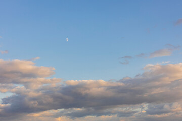 Beautiful view of blue sky with white clouds and a crescent moon.