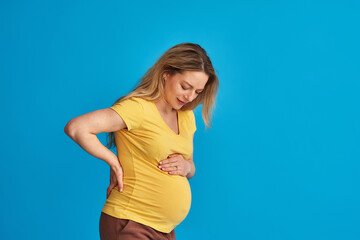 abdominal pain of a pregnant woman on a blue background. labor pains before childbirth. back pain...