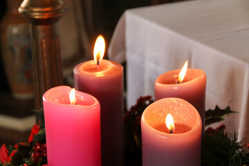 Obraz na płótnie Canvas Four purple candles lit over an advent wreath for Sunday Mass in the church