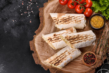 Delicious fresh shawarma with meat and vegetables on a dark concrete table