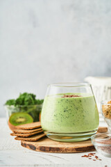 Detox green smoothie with kale, spinach and kiwi on a light gray slate, stone or concrete background. Top view with copy space.