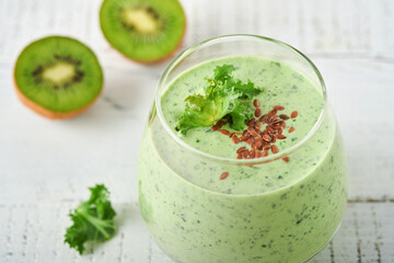 Detox green smoothie with kale, spinach and kiwi on a light gray slate, stone or concrete background. Top view with copy space.