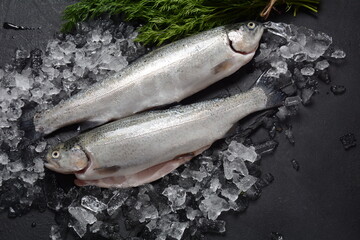 Fresh trout on dark table with lemon, pepper and dill. Tasty fish ready for cooking. Healthy seafood and dieting concept.