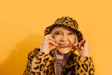 Senior woman bites her neck chain while looking at the camera