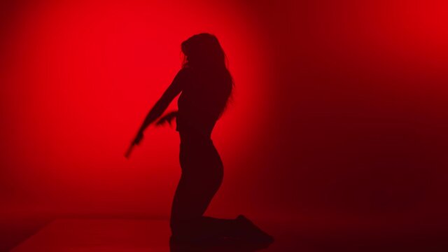 Shadow of seductive lady slim body performing strip plastic dance movement. Wide shot on RED camera