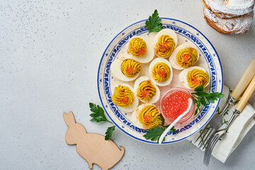 Stuffed eggs with red caviar and paprika on plate for appetizer easter table, top view, copy space. Traditional dish for Happy Easter holiday.
