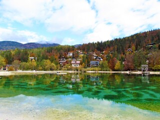 Lake Jasna near Kranjska Gora in Gorenjska, Slovenia in autumn with a reflection in the lake and forest covered hills and houses