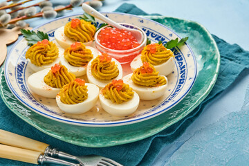 Stuffed eggs with red caviar and paprika on plate for appetizer easter table, top view, copy space. Traditional dish for Happy Easter holiday.