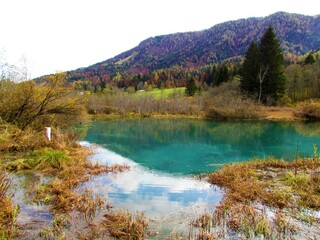 Beautful lake az Zelenci near Kranjska Gora, Gorenjska, Slovenia with a reflection in the lake and hills behind covered in autumn colored forest