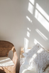Piece of the interior of room with an armchair, bed and falling sun rays.