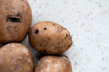 A few organic potatoes on the table. Made in natural light, soft shadows.