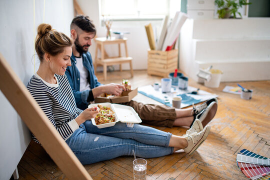 Couple eating lunch indoors at home, relocation, diy and food delivery concept.