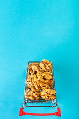 Food cart filled with peeled walnuts on a blue background. Copy space.