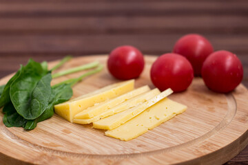 cheese, tomatoes, spinach on a wooden board.