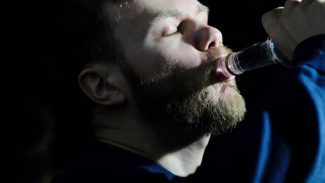 alcoholic man drinking vodka from a bottle in the dark, alcohol addiction.