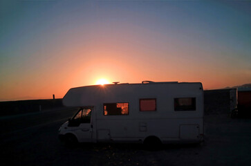 The bright sun setting over the camper van