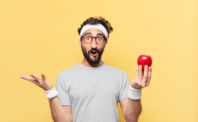young crazy bearded athlete surprised expression and holding an apple and holding an apple