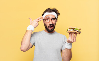 young crazy bearded athlete sad expression and holding a sandwich