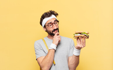 young crazy bearded athlete thinking expression and holding a sandwich