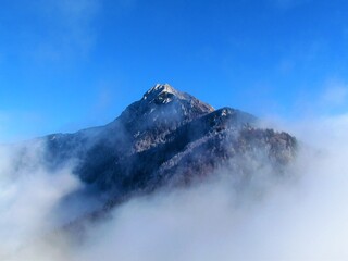 Scenic view of Storzic mountain in Kamnik-Savinja alps, Gorenjska, Slovenia with mist covering the slopes and trees in the forest covered in frost