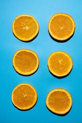 Orange slices parallel to each other in a vertical photo on a blue background