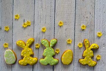 Frame from cookies for Easter. Bunny and eggs decorated with icing dry on white rustic wooden table. Homemade Easter gingerbread. Bright colors.