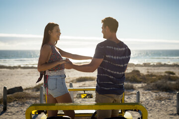Happy caucasian couple in beach buggy by the sea holding hands