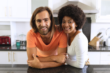 Portrait of happy diverse couple in kitchen smiling and embracing