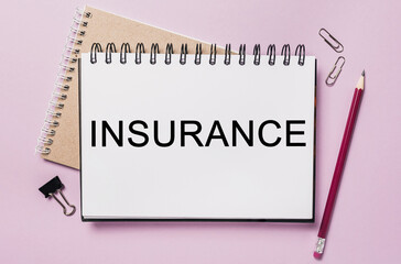 Text INSURANCE on a white notepad with office stationery background. Flat lay on business, finance and development concept