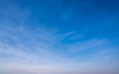 Naklejka na ściany i meble background of blue sky with wispy white clouds towards the bottom