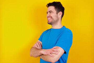 young handsome caucasian man wearing blue t-shirt against yellow background cross hands look copy space