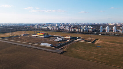 Flying over a field on the outskirts of the city. The city outskirts are visible on the horizon.