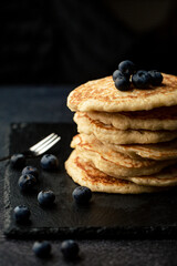 Stack of blueberry pancakes with syrup and fresh blueberries
