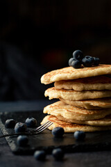 Stack of blueberry pancakes with syrup and fresh blueberries