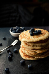 Stack of blueberry pancakes with syrup and fresh blueberries