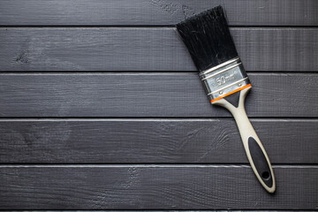 Paint brush on black plank background.
