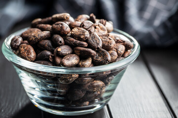 Roasted cocoa beans in glass bowl.