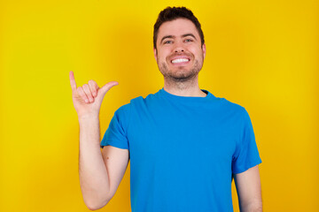 young handsome caucasian man wearing blue t-shirt against yellow background Through Megaphone with Available Copy Space