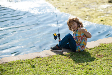 Happy childhood. Child fishing on the lake. Boy with spinner at river. Portrait of excited boy...
